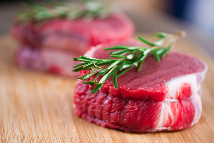 Two pieces of raw beef tenderloin with sprigs of rosemary