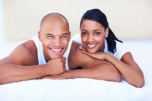 A smiling couple lying on their bed at home