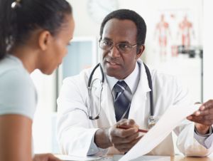 A male doctor pointing to a chart as he talks to his female patient