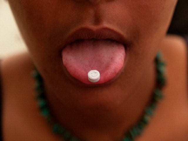 Girl with ecstacy tablet on her tongue, smiley faced pill, Uk 2004