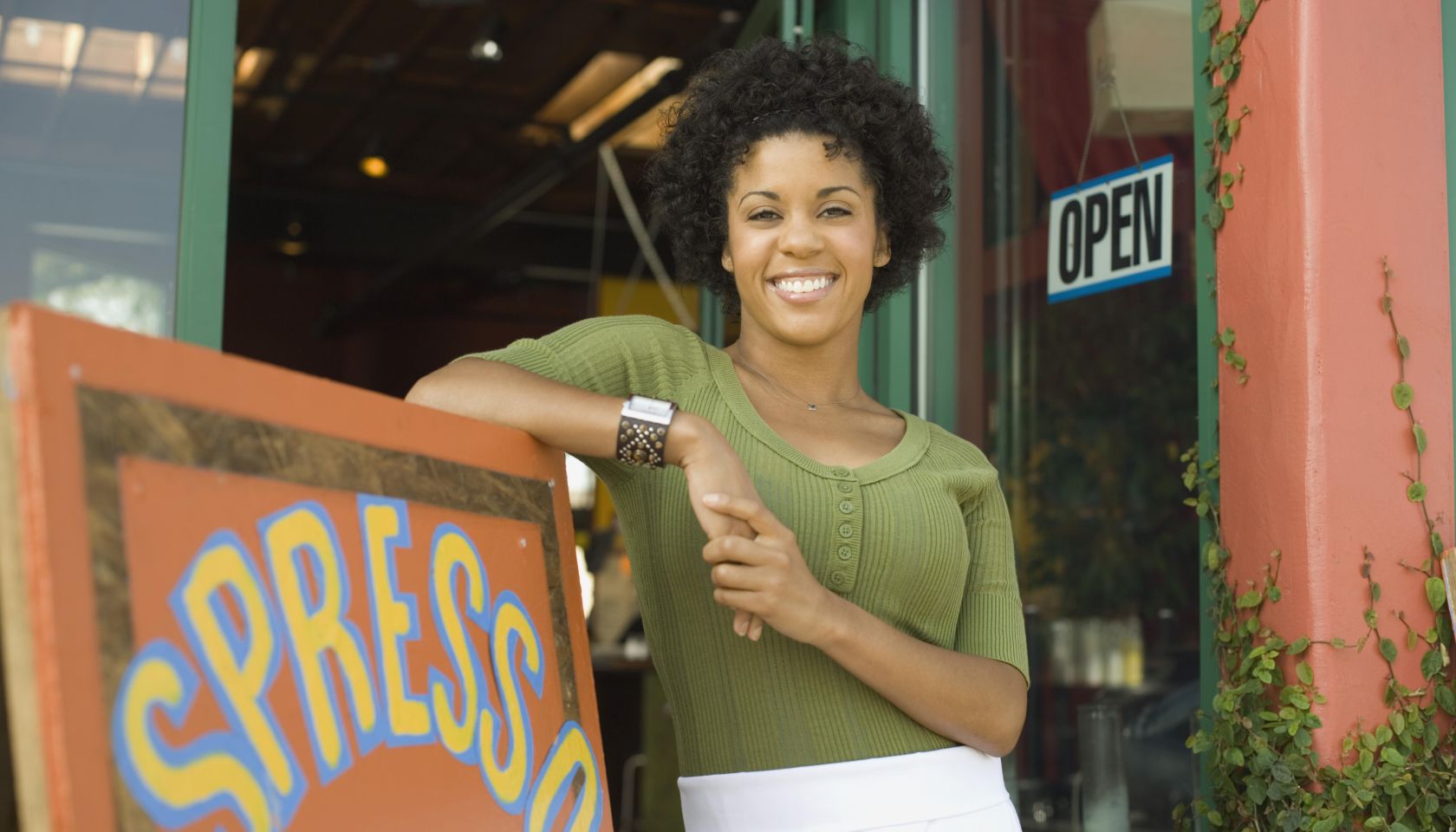 Woman leaning against coffee shop sign