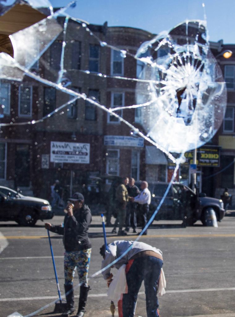 People sweeping and cleaning up the area in front of the Check Cashing store that was looted Monday night after Freddie Gray's funeral in Baltimore.