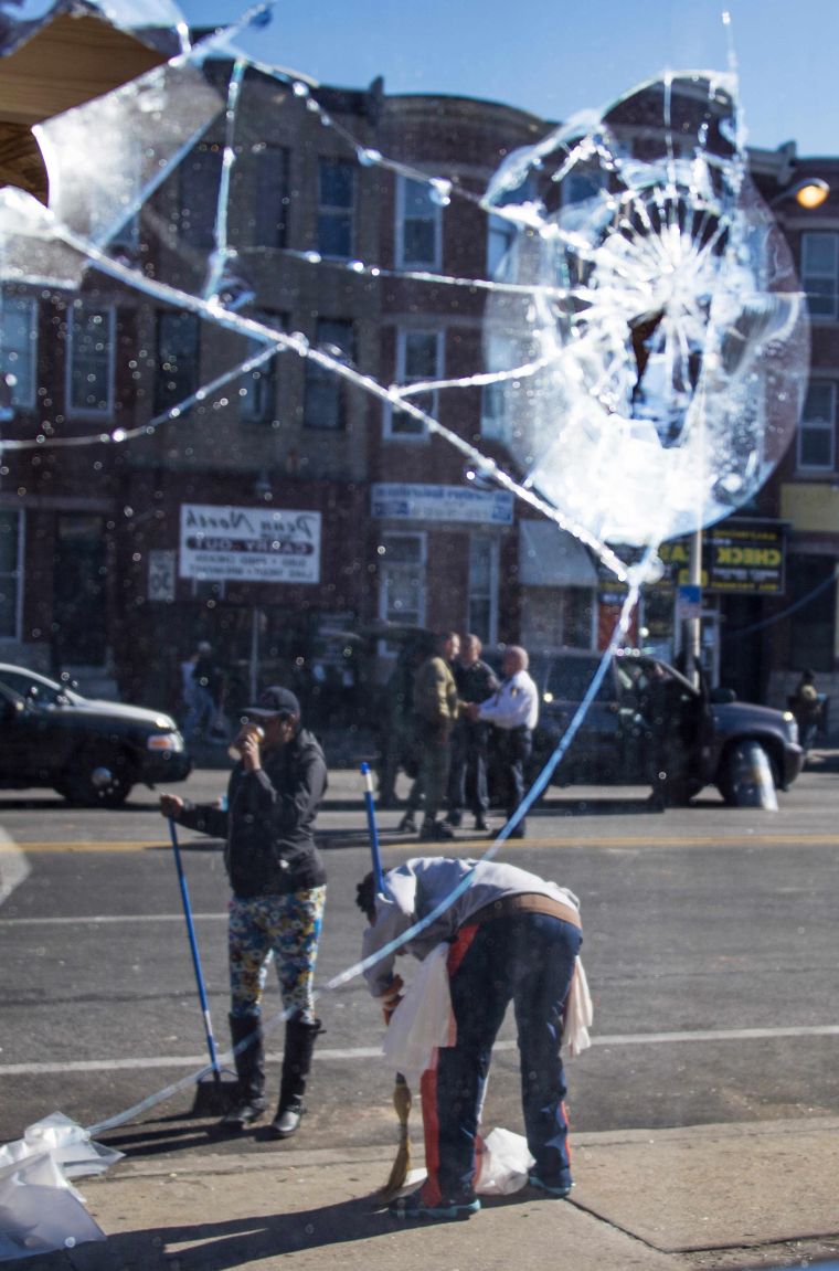 People sweeping and cleaning up the area in front of the Check Cashing store that was looted Monday night after Freddie Gray’s funeral in Baltimore.