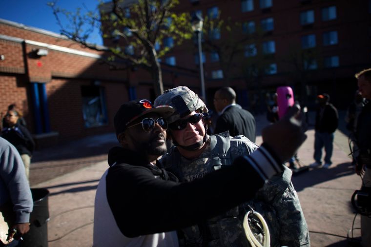 A man takes a selfie with a National Guard Officer Tuesday morning as others help clean up the city.