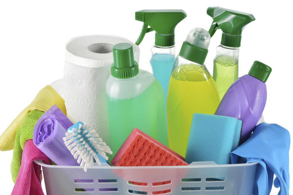 Close up of cleaning products and supplies in a basket. Cleaners, microfiber cloths, gloves in a basket isolated on white background. Cleaning kit.