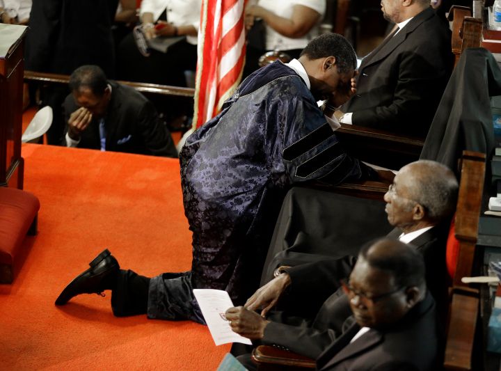 The Rev. Norvel Goff, right, prays at the empty seat of the Rev. Clementa Pinckney.