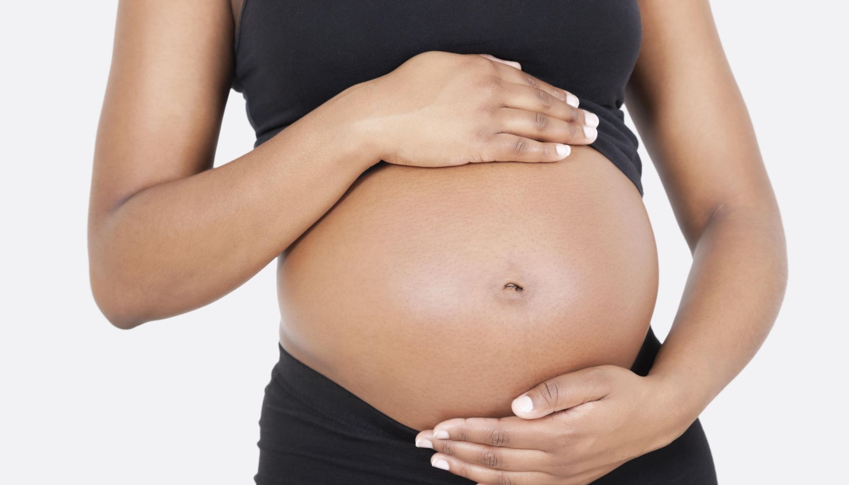 Mid section of pregnant woman touching abdomen over white background