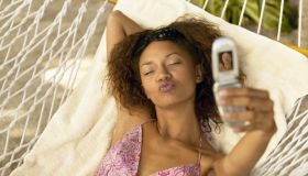 Woman in hammock taking picture with camera phone, puckering lips