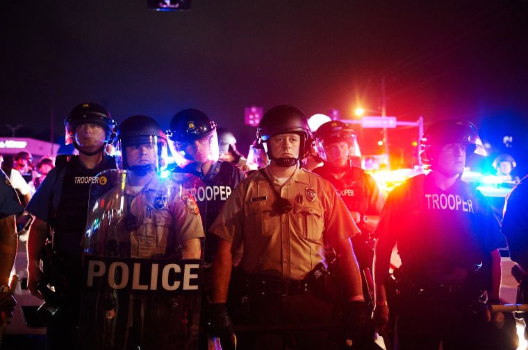 2015: Police stand to maintain the crowd after shots rang out on the anniversary of Mike Brown’s death.