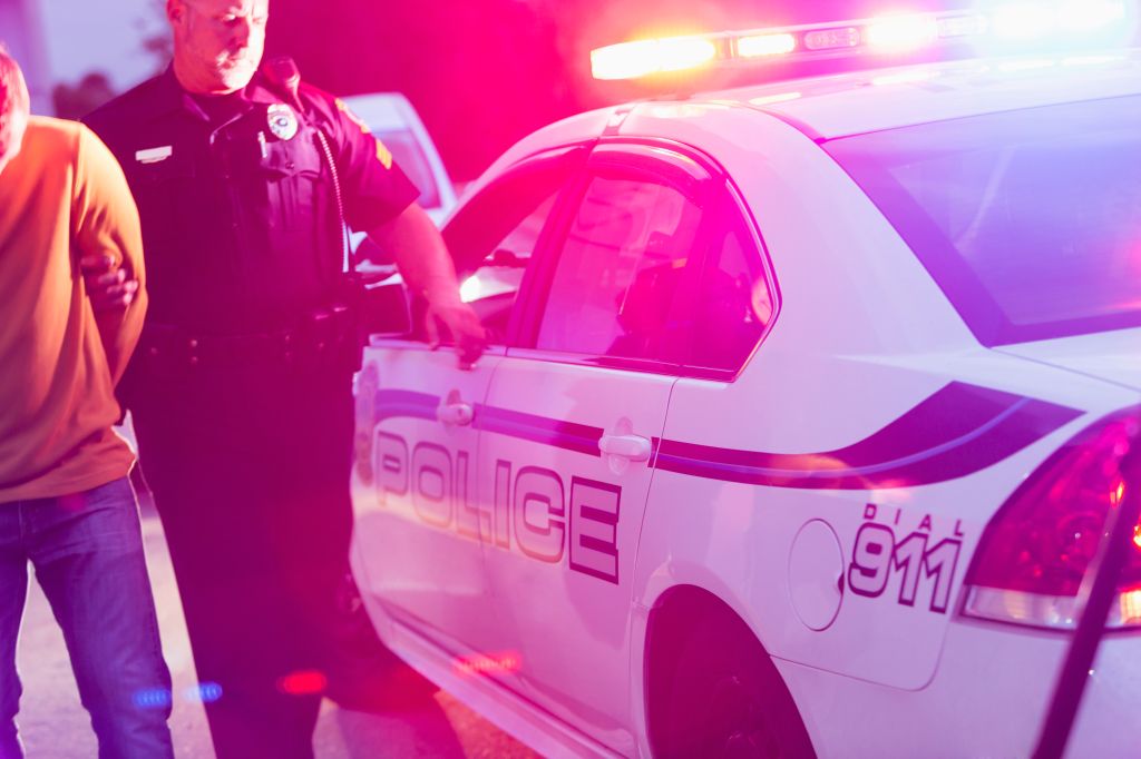 Police officer arresting a young man at night