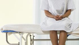 Female patient sitting on gurney in hospital gown, low section
