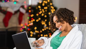 African American woman buying Christmas gifts online with credit card