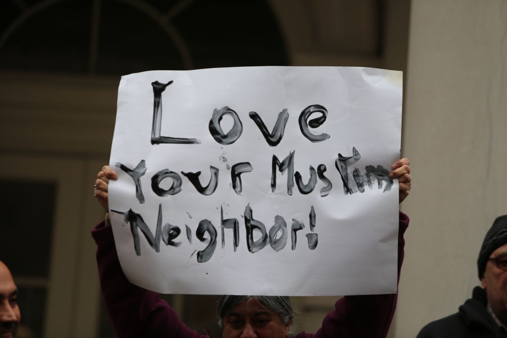 Hand-lettered Love Your Muslim Neighbor sign held aloft.