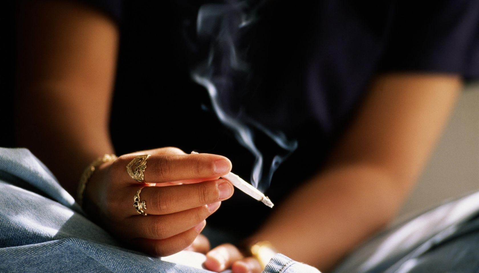 Teenager (16-18) smoking hand rolled cigarette
