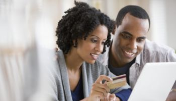 Couple holding credit card and using laptop