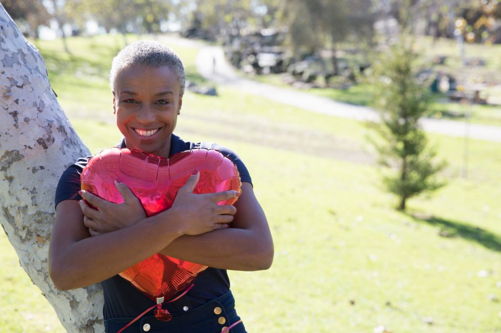 Mature woman hugging red heart-shaped balloon, Hahn Park, Los Angeles, California, USA