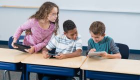 Three elementary school students, digital tablets