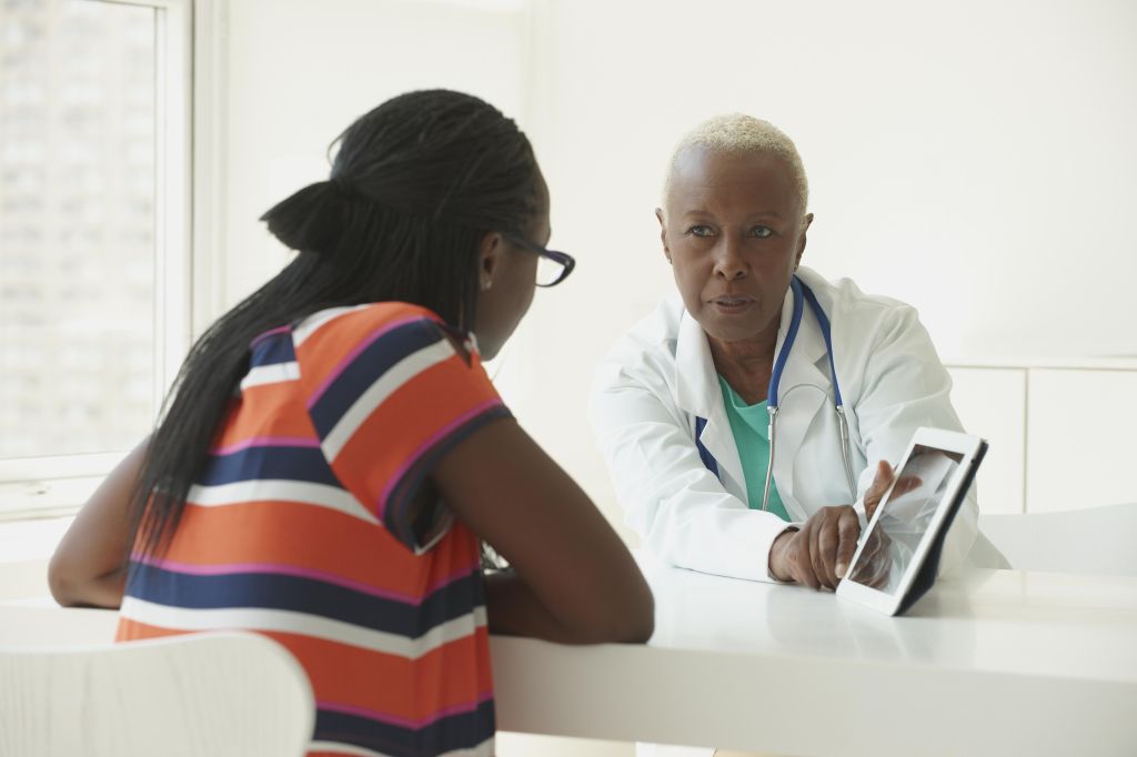 Black doctor using digital tablet with patient