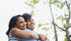 Adult woman embracing mother from behind