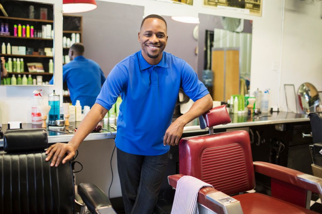 Black barber smiling in retro barbershop