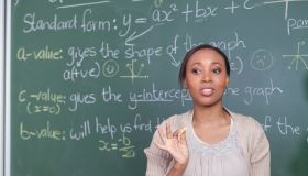 Head and shoulder of female teacher with mathematics equations on the chalkboard, Cape Town, South Africa