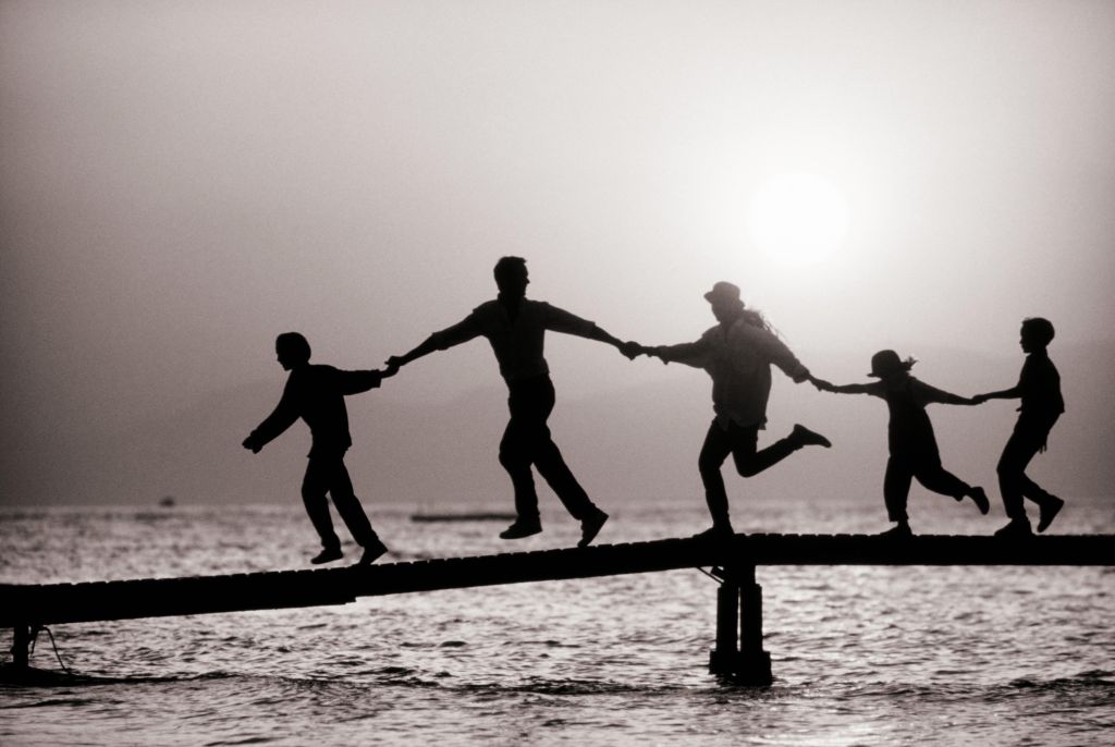 FAMILY JOINING HANDS ON A DOCK IN BLACK AND WHITE