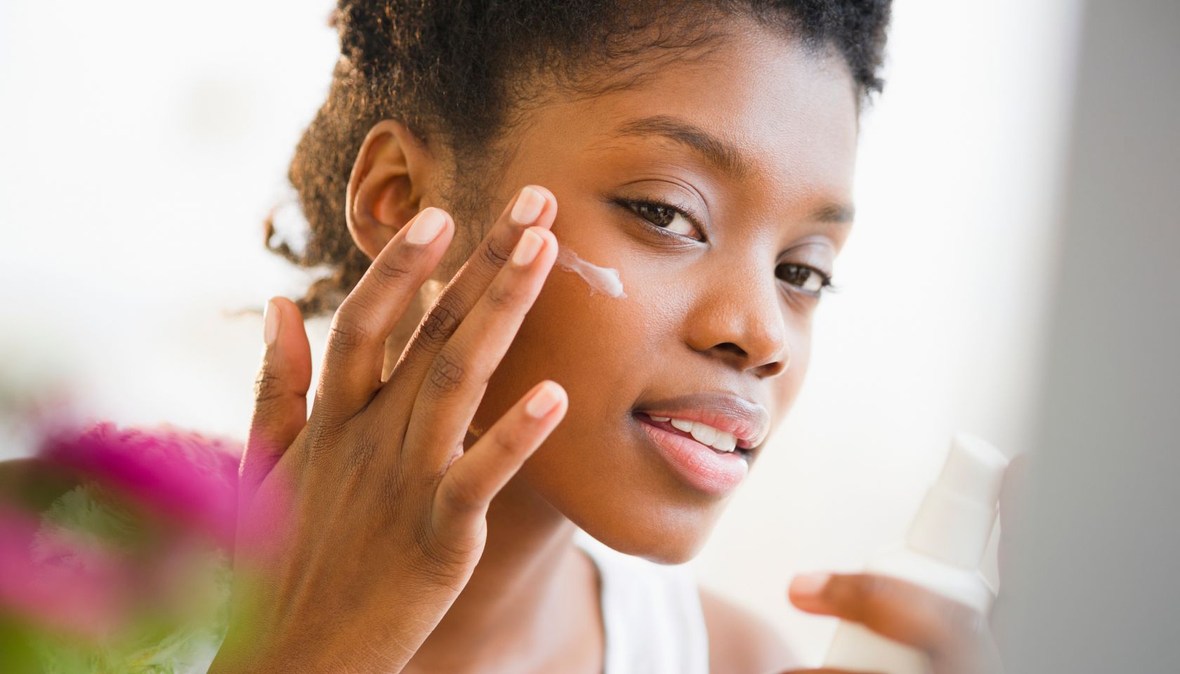 Black woman putting on face lotion