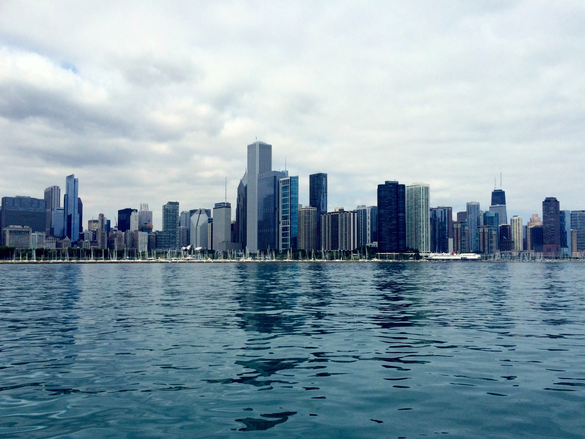 Cityscape In Front Of River Against Cloudy Sky