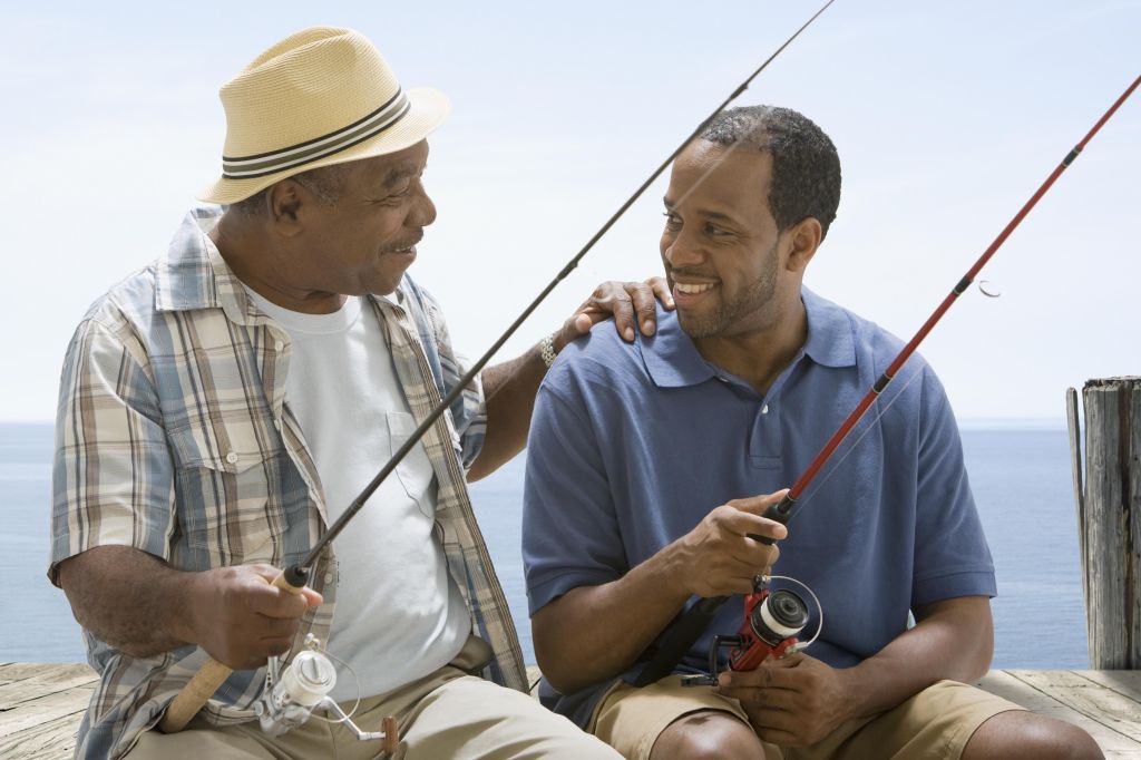 Father clasping son's shoulder while fishing
