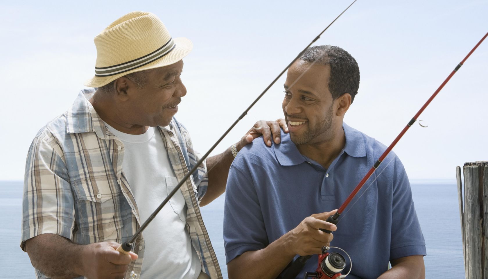 Father clasping son's shoulder while fishing