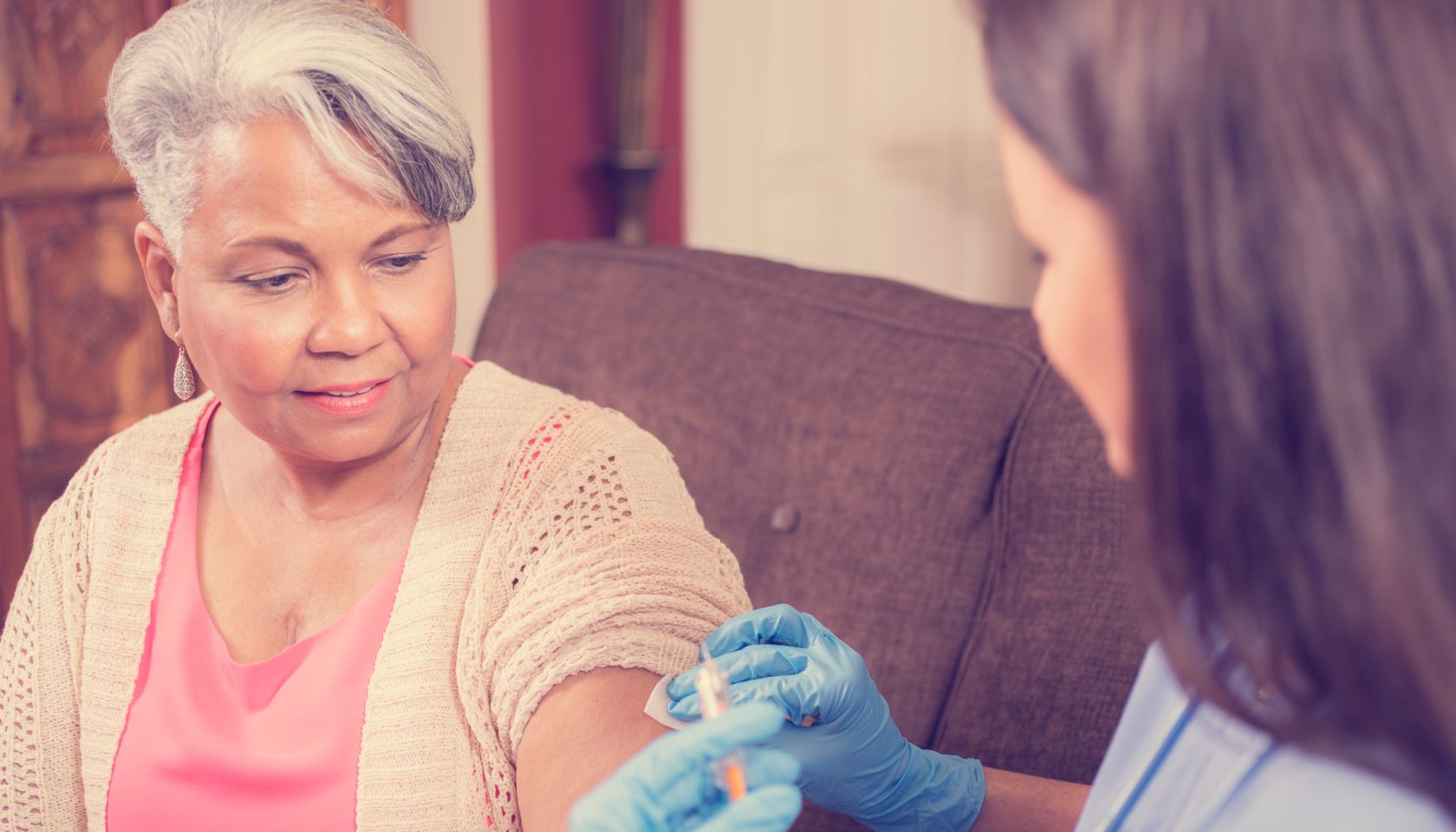 Home healthcare nurse giving injection to senior adult woman.