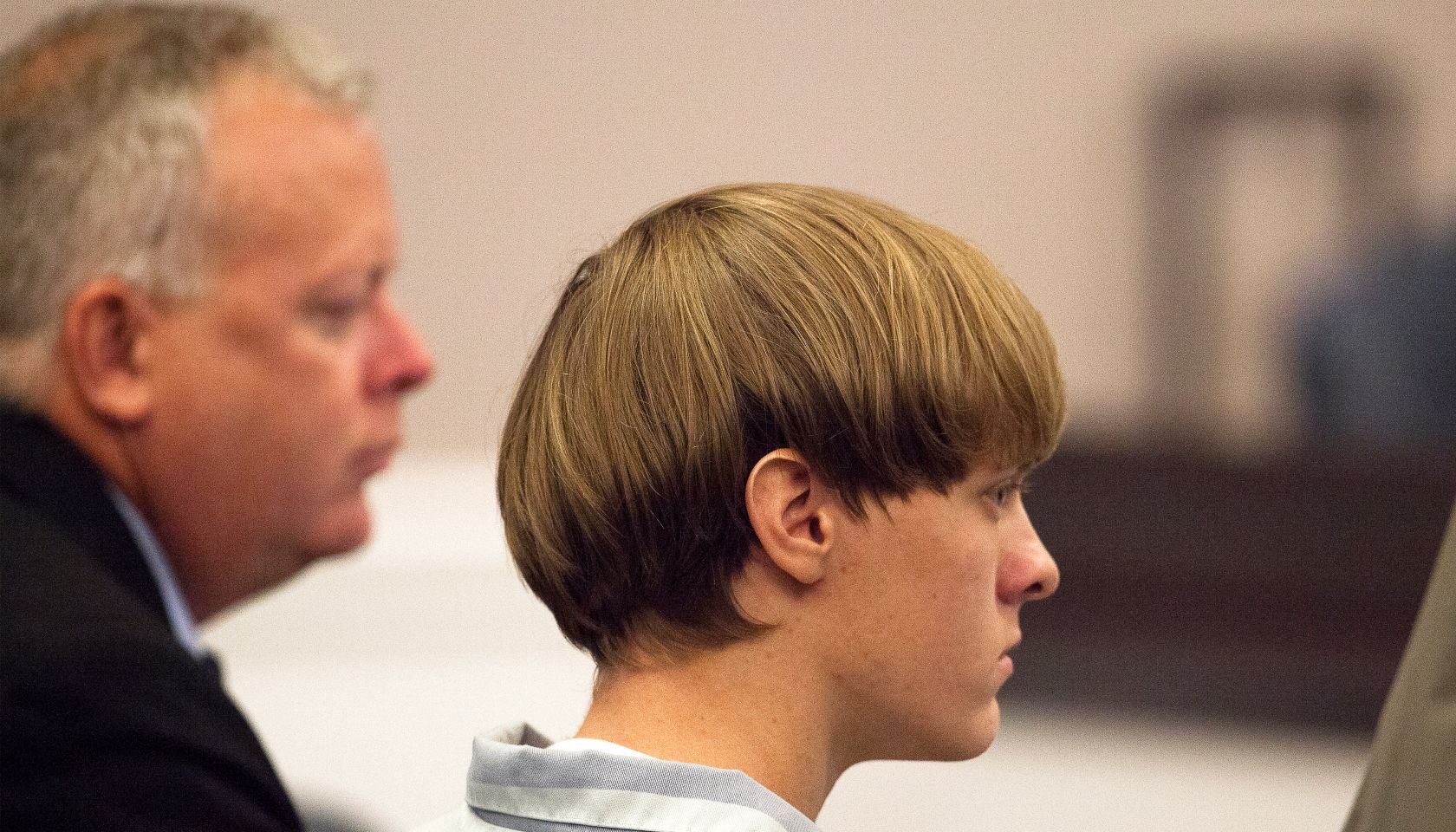 Dylann Roof (R), the 21-year-old man charged with murdering nine worshippers at a historic black church in Charleston last month, is helped to his chair by chief public defender Ashley Pennington during a hearing at the Judicial Center in Charleston