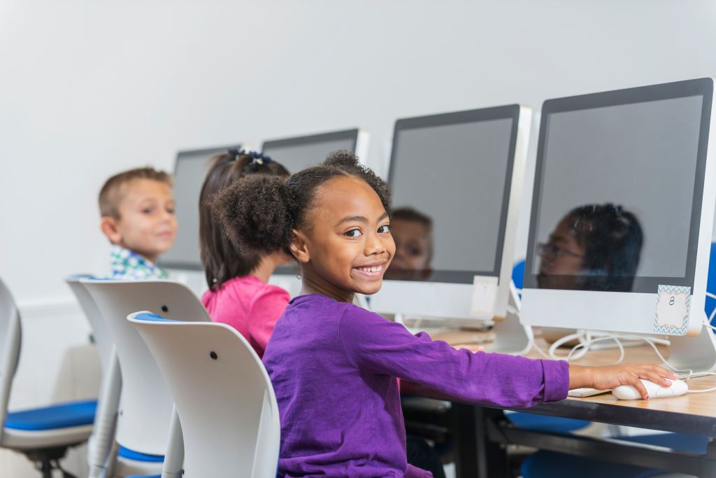Black and Hispanic girl using computer in classroom