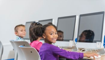 Black and Hispanic girl using computer in classroom