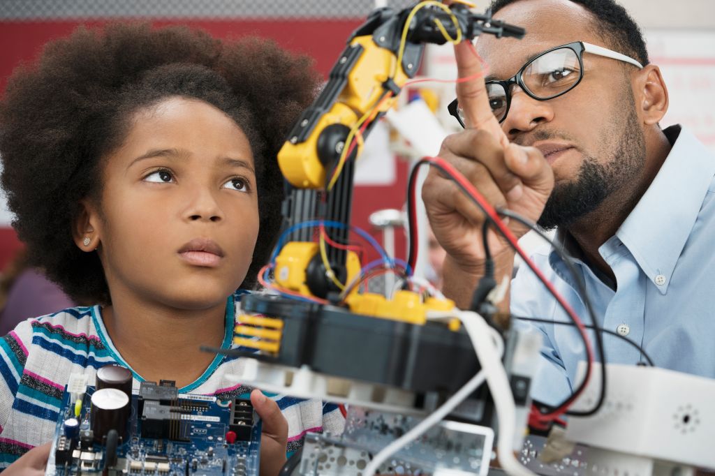 Black teacher helping student with robotics