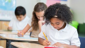 Confident African American private school student takes test in class