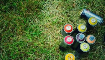 High Angle View Of Colorful Spray Paints On Grassy Field