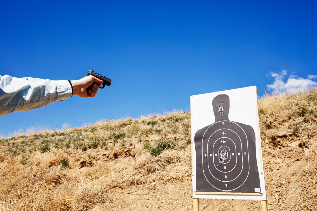 Shooting handgun at human silhouette target.