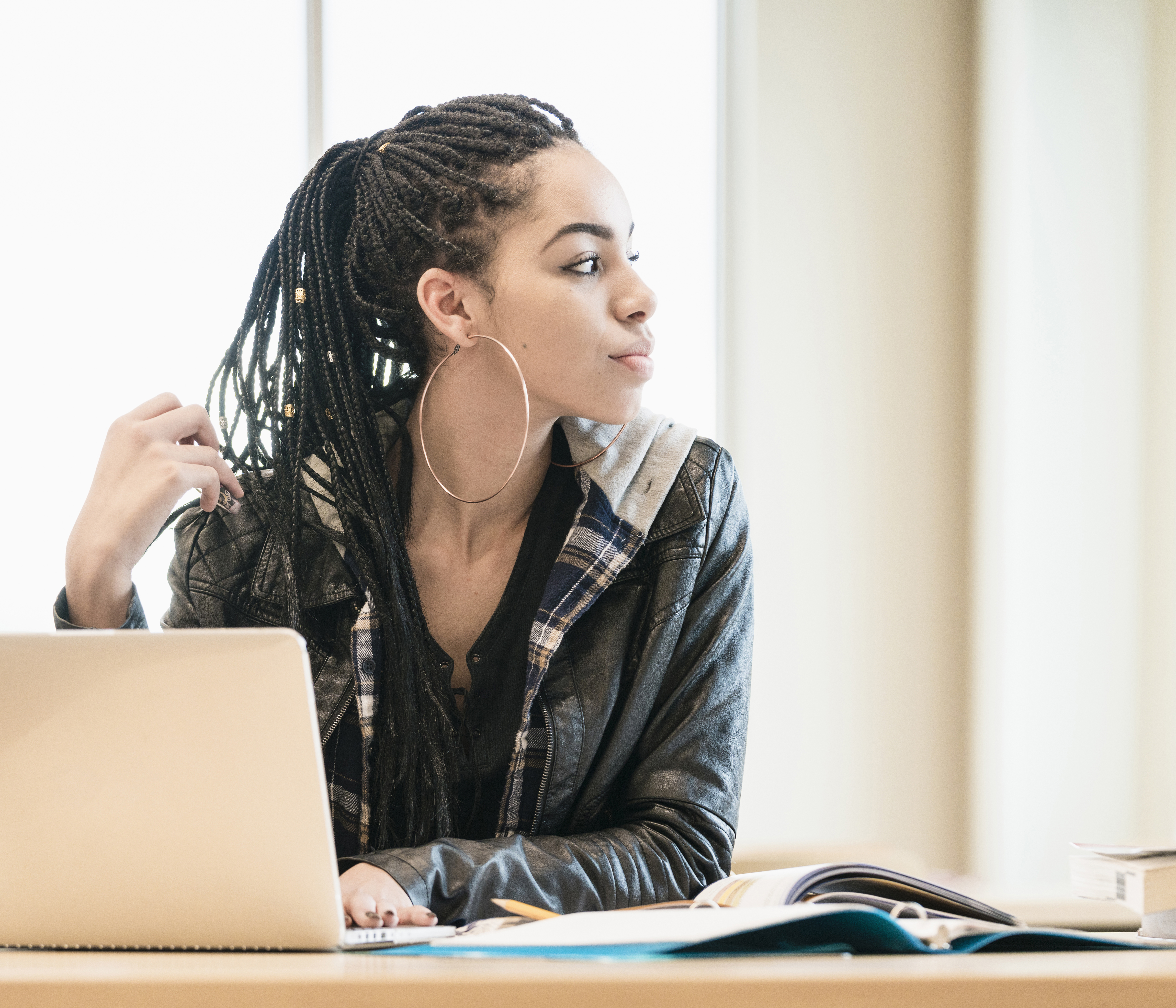 Black teenage girl looking away from laptop