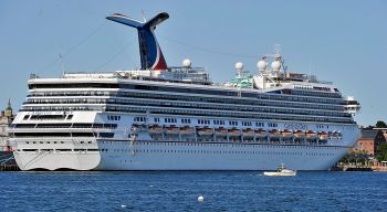 On Tuesday, September 17, 2013, a lobster boat is dwarfed by the size of the Carnival Glory, a cruis