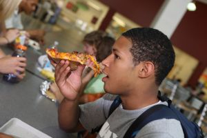 High school student eating pizza in school cafeteria