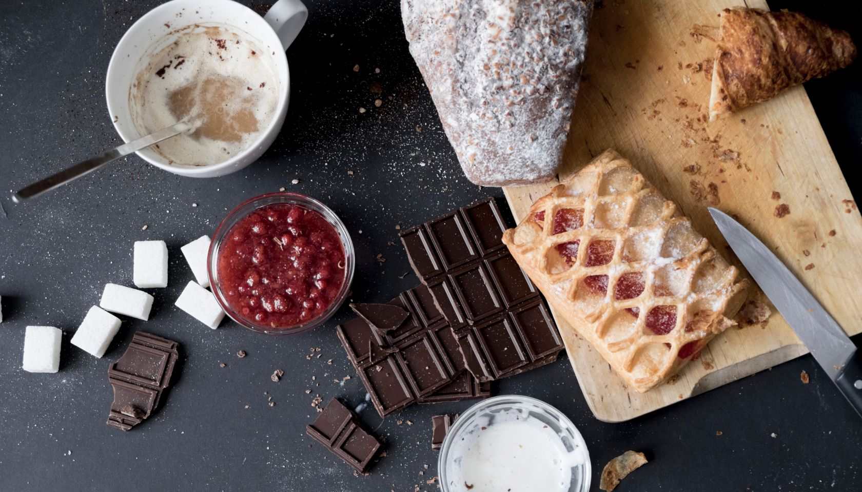 Overhead view of apple strudel, chocolate, cake and ingredients on kitchen table