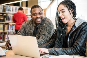 Teacher and student using laptop in library