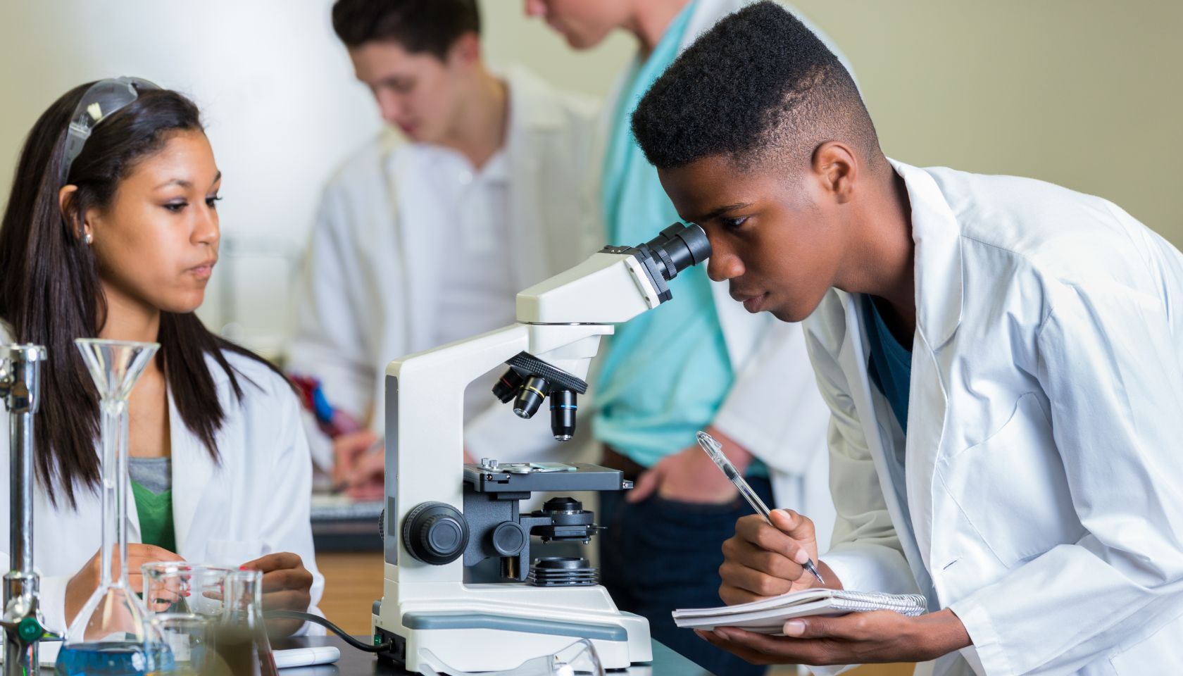 African American high school student record observations in science lab
