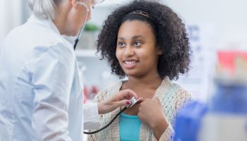 Physician listens to teenage patient's heart