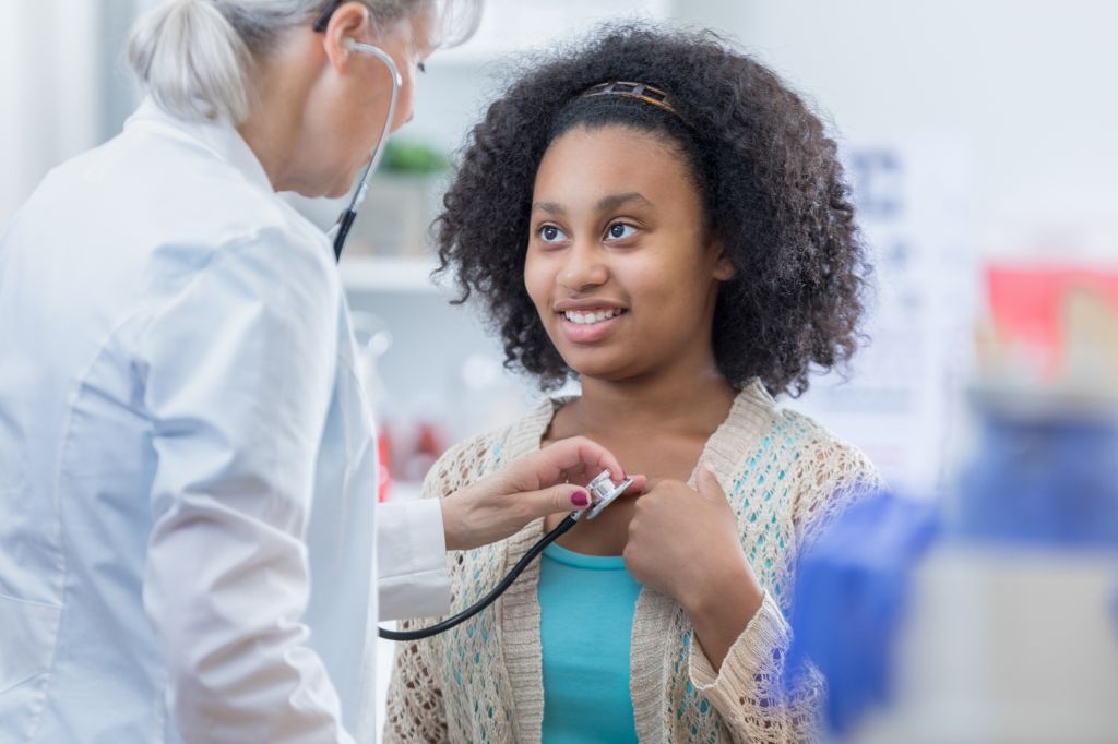 Physician listens to teenage patient's heart