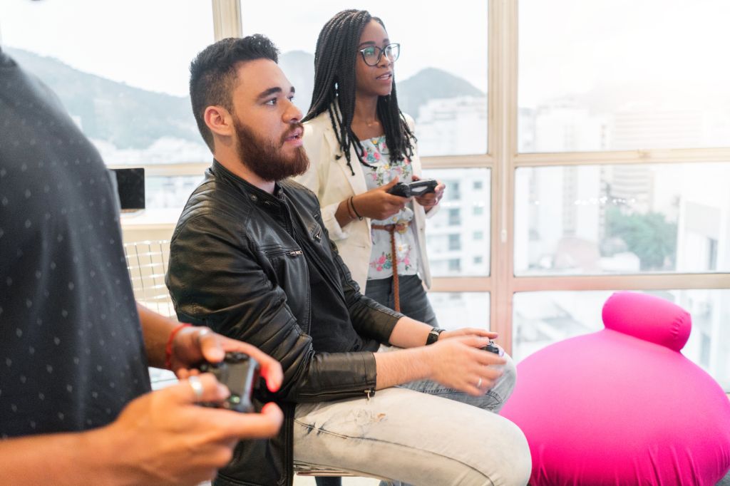 colleagues playing video game during break in creative office