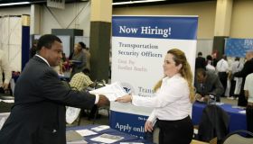 A woman handing a brochure to a man at the Transportation Security Administration booth at a job fair in Miami