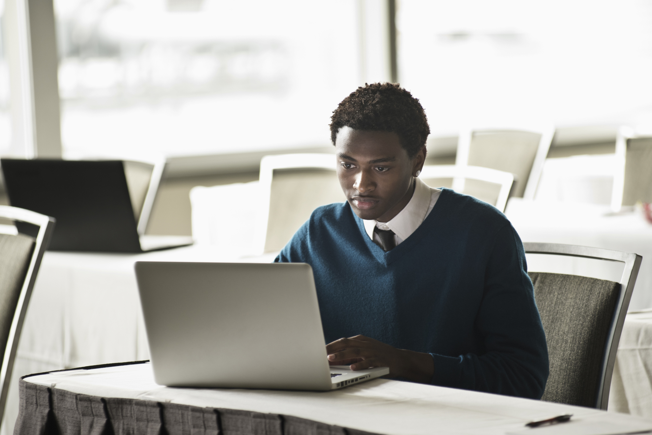 Mixed race businessman using laptop in convention room