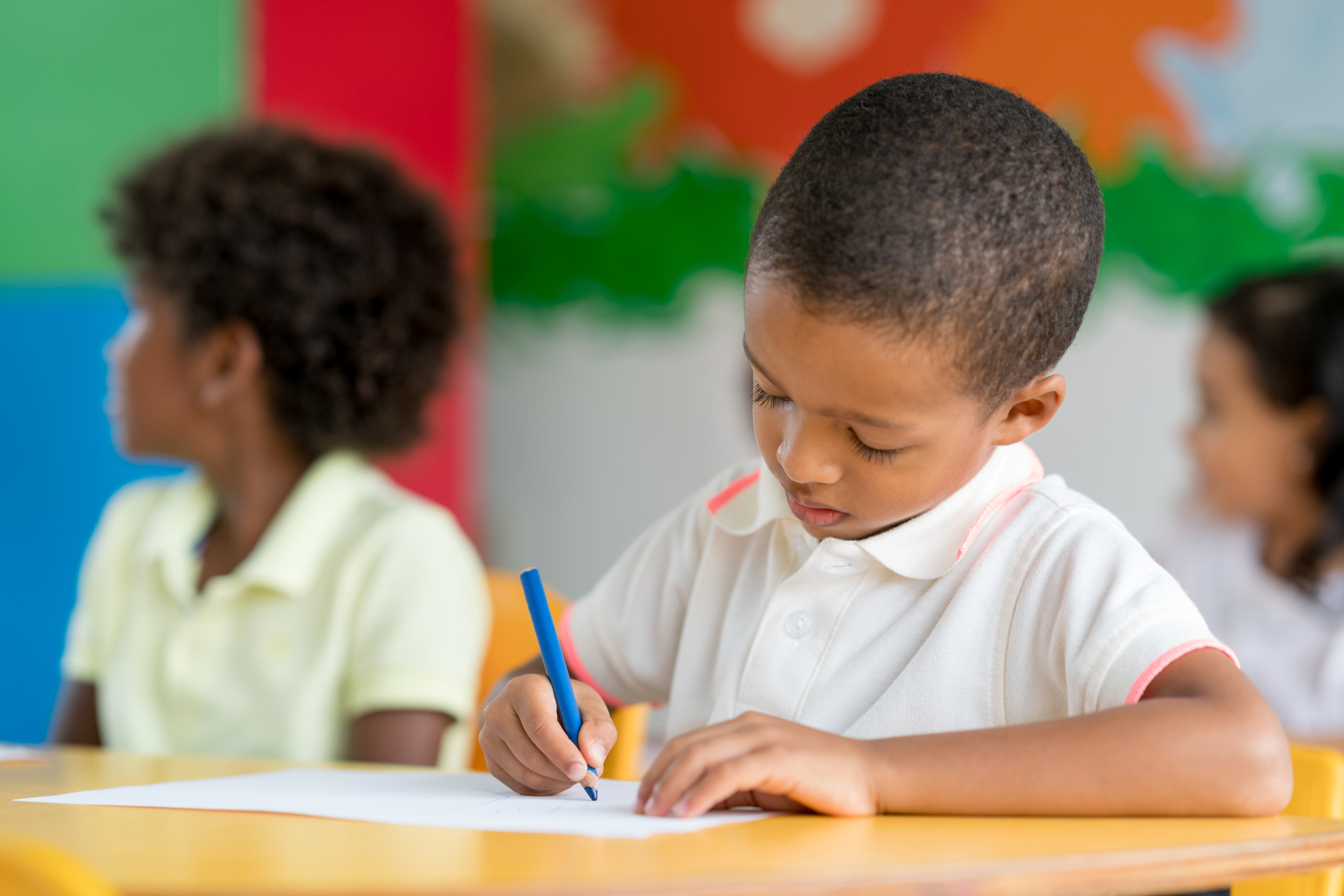 Portrait of a boy coloring at school